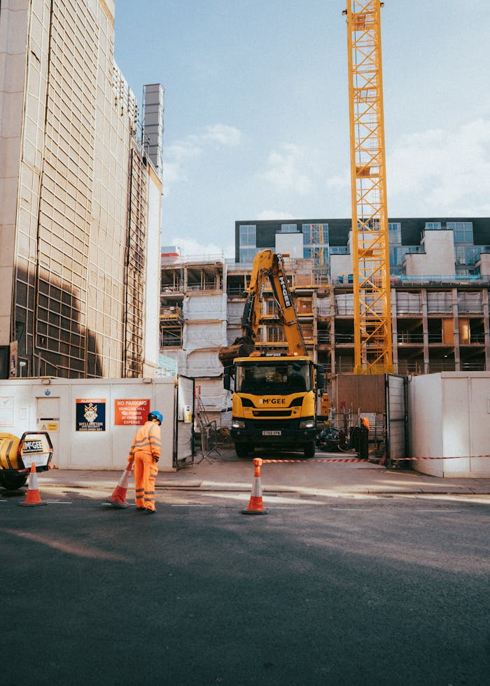 Services City construction site featuring worker, machinery, and urban surroundings in progress under bright daylight.